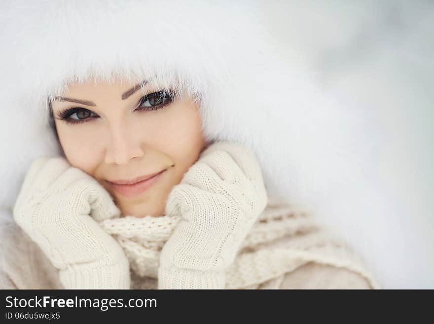 Winter portrait of beautiful smiling woman with snowflakes in white furs