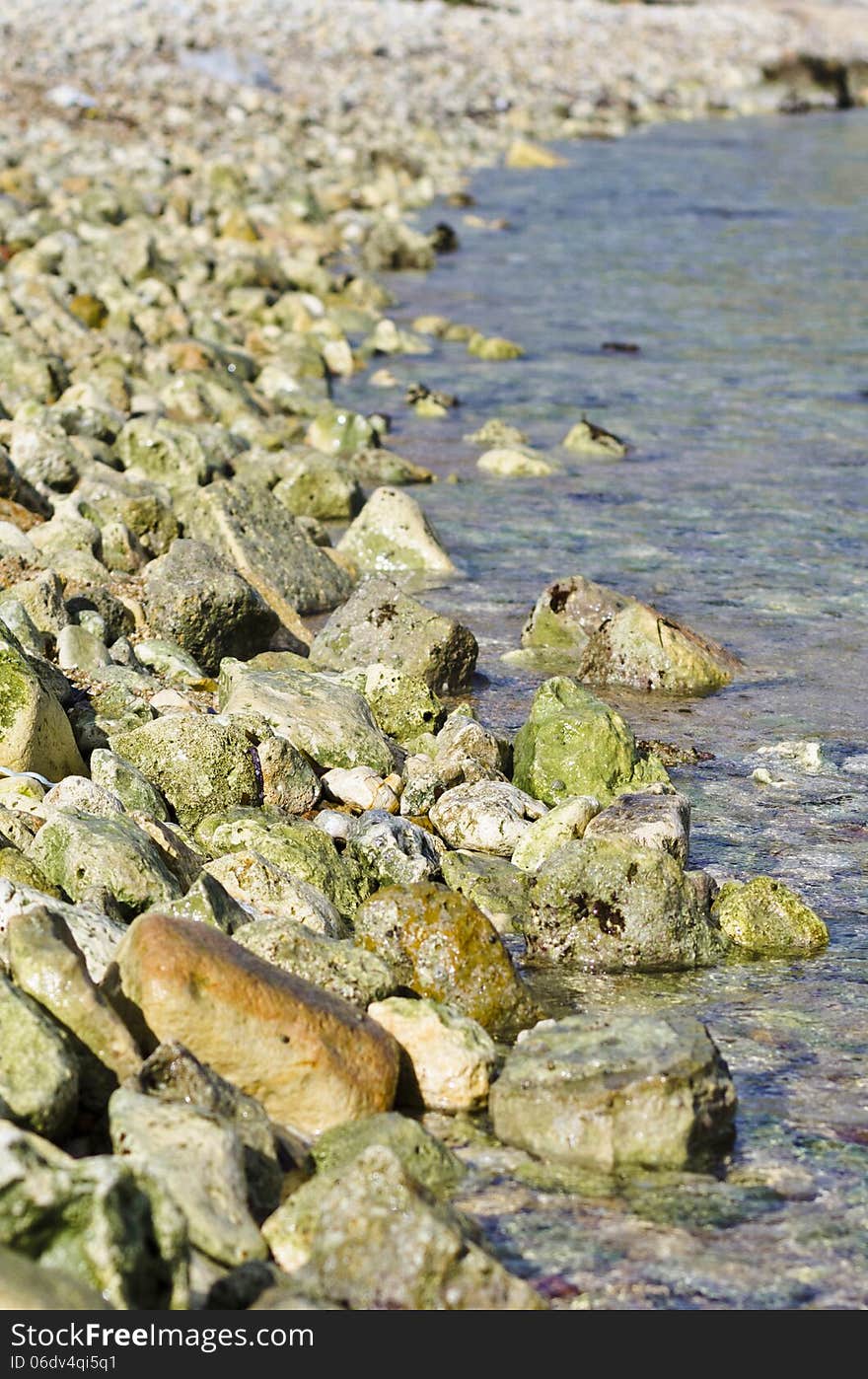 Colorful stones and pebbles forming a shoreline at a rocky beach in the maltese islands. Colorful stones and pebbles forming a shoreline at a rocky beach in the maltese islands