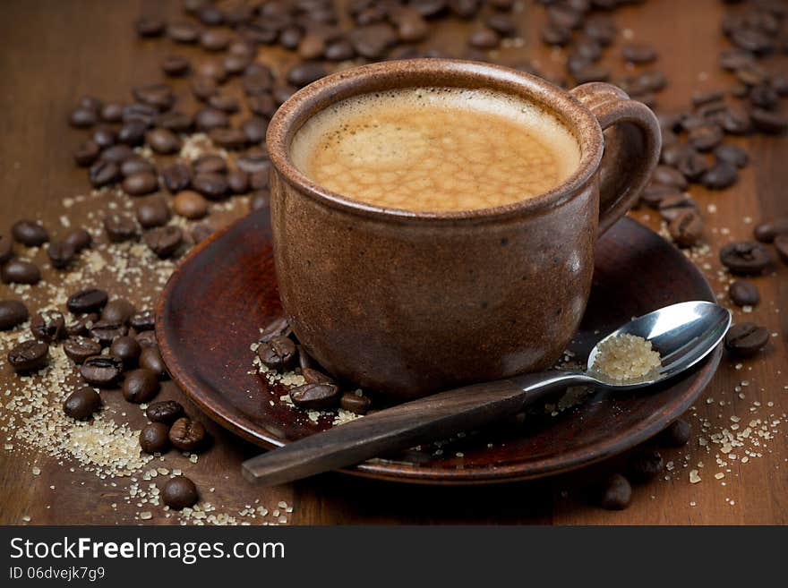 Espersso cup, sugar and coffee beans on wooden table, selective focus, close-up