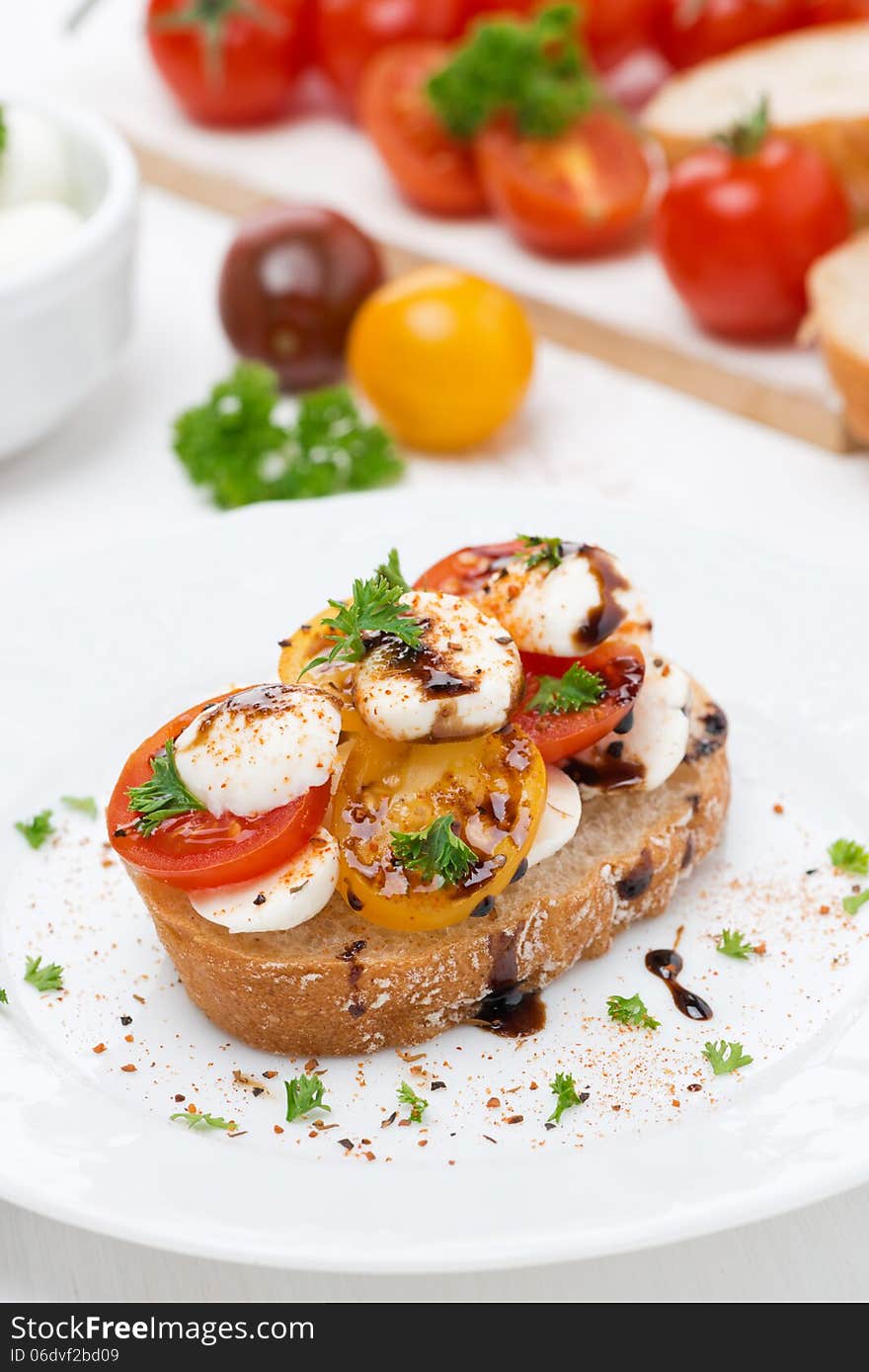 Piece of ciabatta with mozzarella and colorful cherry tomatoes on the plate, vertical