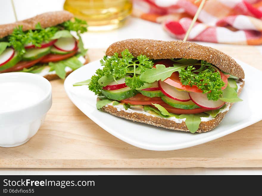 Sandwich with cottage cheese, greens, vegetables on wooden board