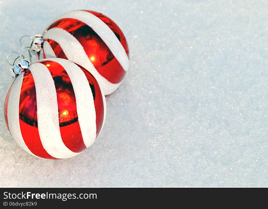 Red and white striped Christmas ornaments on fresh snow background with copy space, ideal for greeting card or party invitation. Red and white striped Christmas ornaments on fresh snow background with copy space, ideal for greeting card or party invitation.