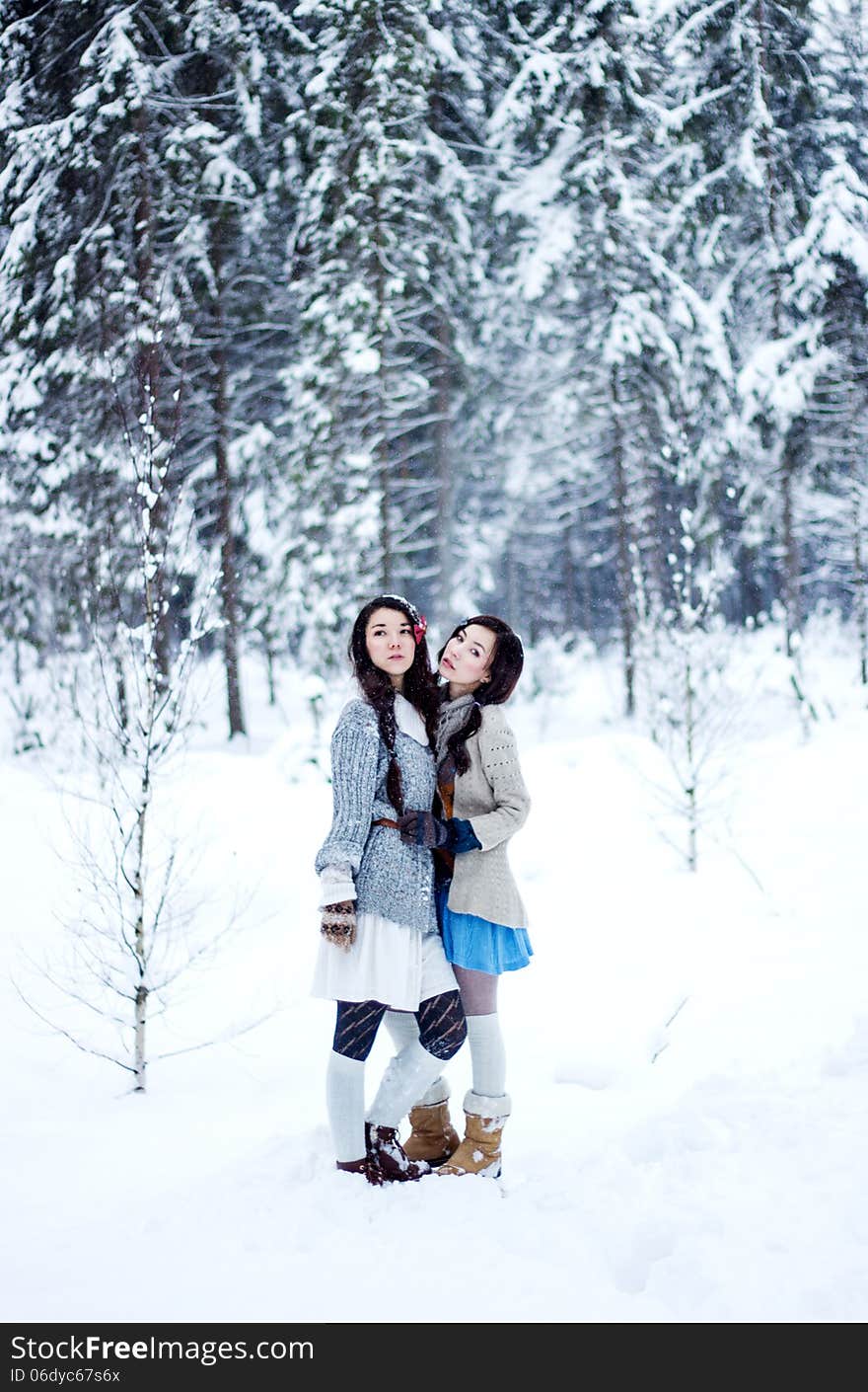 Fashion women in warm sweaters on white snow forest background