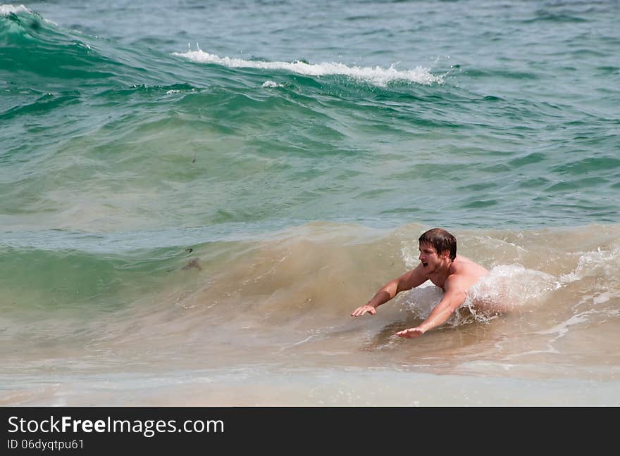 A young man body surfs through waves on a beach in South Africa. A young man body surfs through waves on a beach in South Africa.