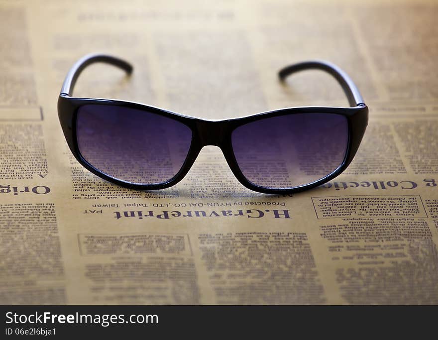 A pair of sunglasses on newspaper background.