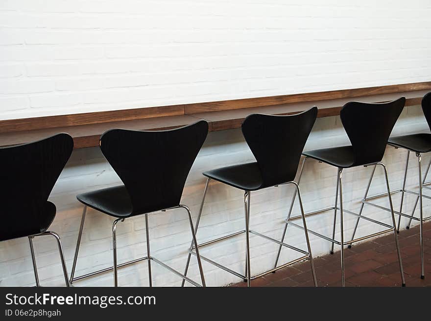 Modern designer minimalistic style chairs in line opposite a white wall. Modern designer minimalistic style chairs in line opposite a white wall