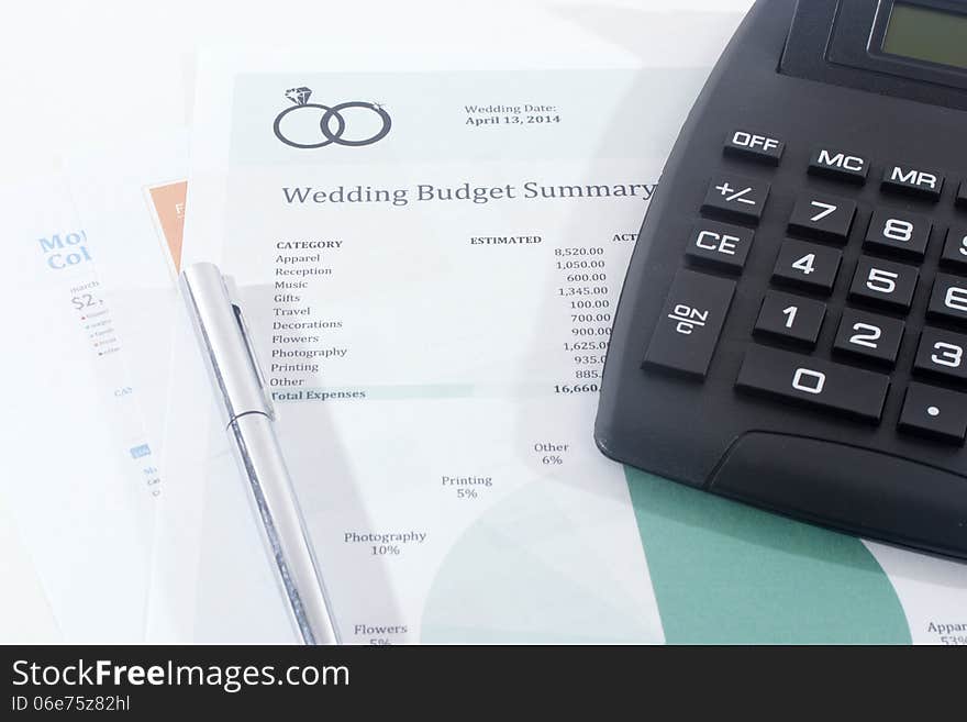 Wedding budget summary estimate with a black calculator and silver pen. Wedding budget summary estimate with a black calculator and silver pen