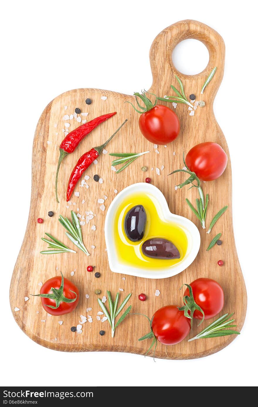 Tomatoes, chili peppers, olive oil, olives and spices on a wooden board, top view, isolated on white