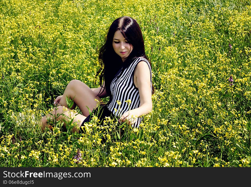 Happy woman sitting on yellow sunny flowers field