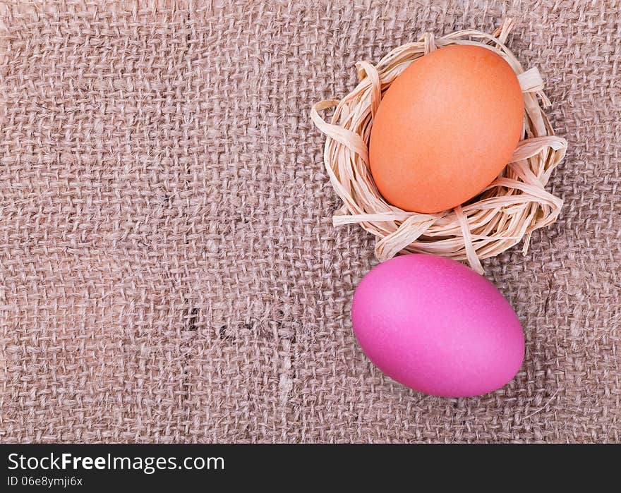 Easter eggs on burlap background, top view