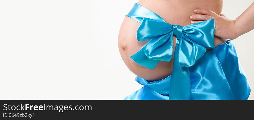 On the abdomen of a pregnant woman tied blue bow. On the abdomen of a pregnant woman tied blue bow