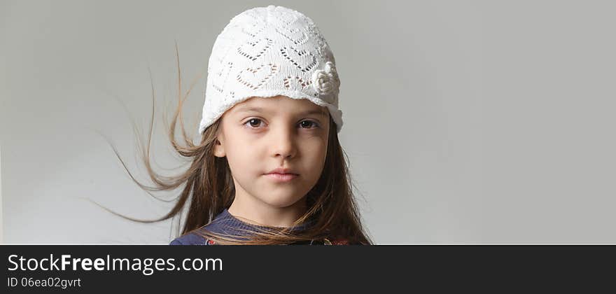 Portrait of a girl in a white knitted cap with flying hair. Portrait of a girl in a white knitted cap with flying hair