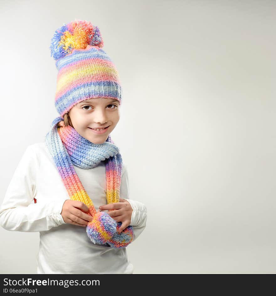 Portrait of girl in knitted hat and scarf on a light background. Portrait of girl in knitted hat and scarf on a light background