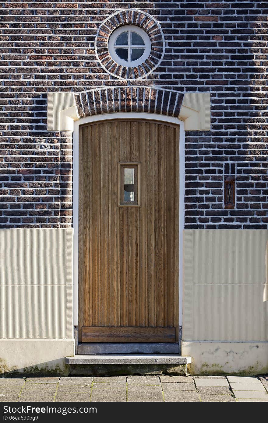 Wooden door and round window in Vlaardingen, the Netherlands. It looks like a person who welcomes you with open arms.