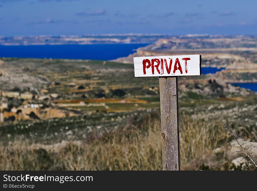 A PRIVAT sign located near a private property in the countryside on the island of Malta. In the blurred background the island of Gozo is visible. A PRIVAT sign located near a private property in the countryside on the island of Malta. In the blurred background the island of Gozo is visible.