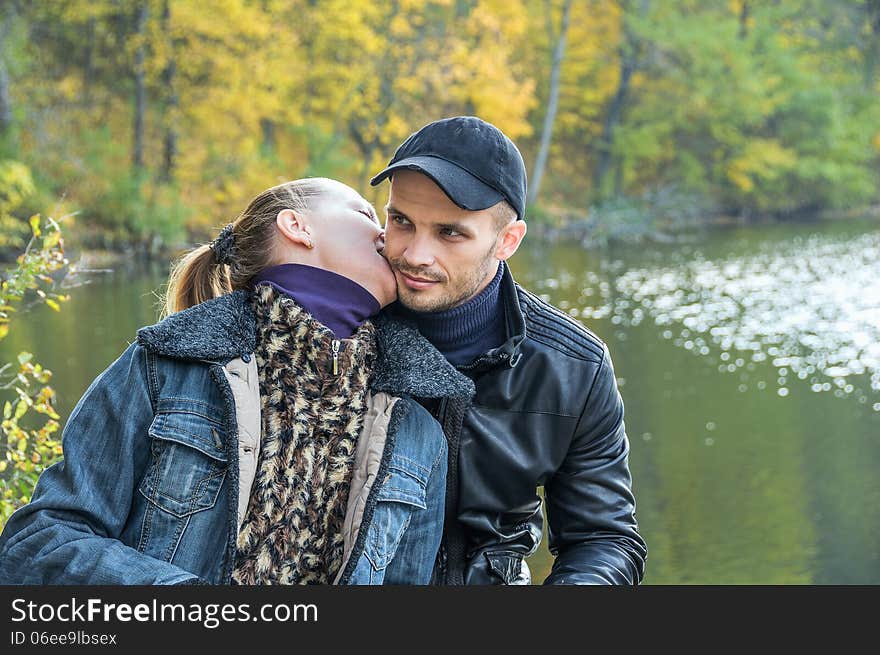 In love couple sitting on a log on the background of a forest pond couple in love