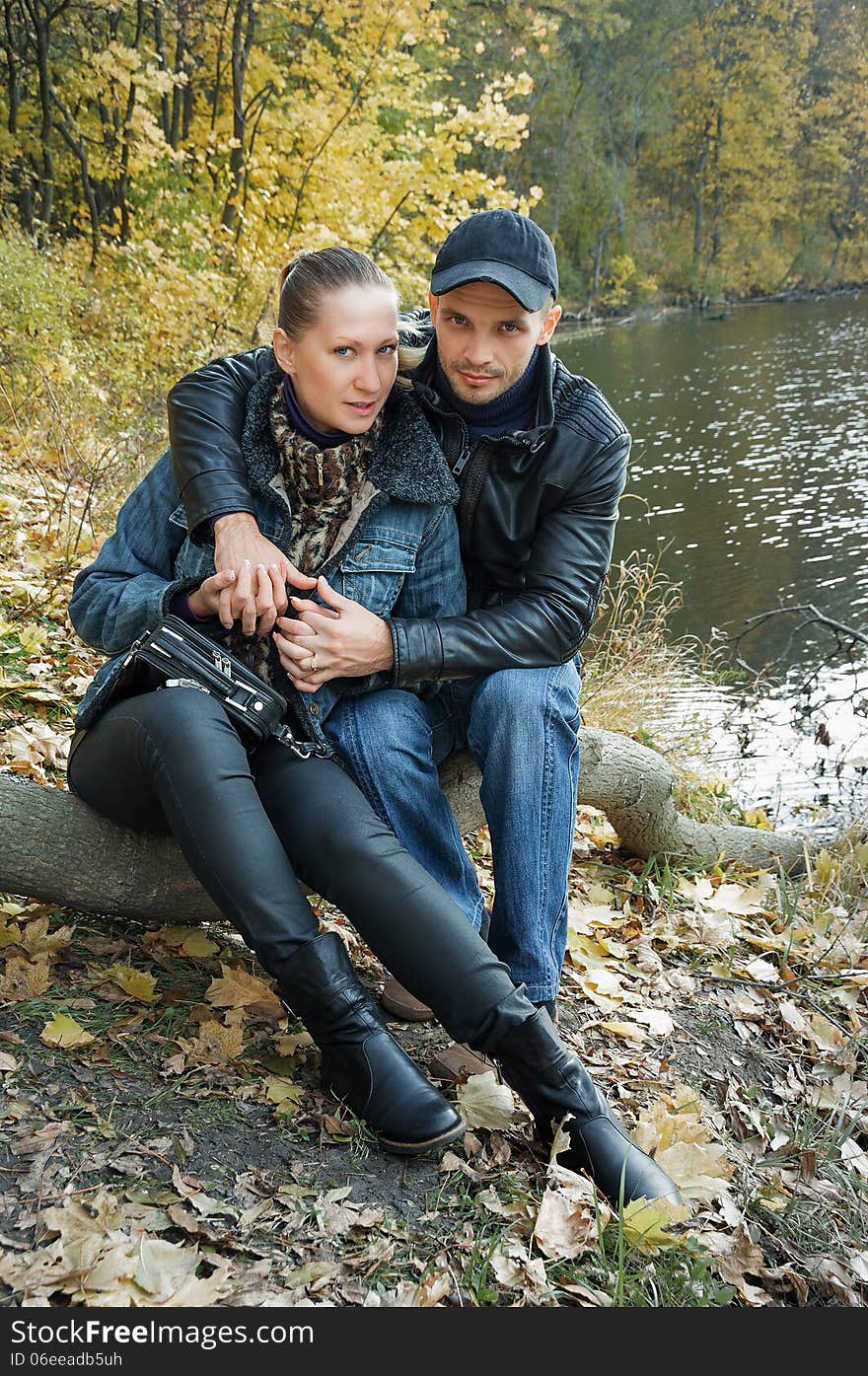 In love couple sitting on a log on the background of a forest pond couple in love