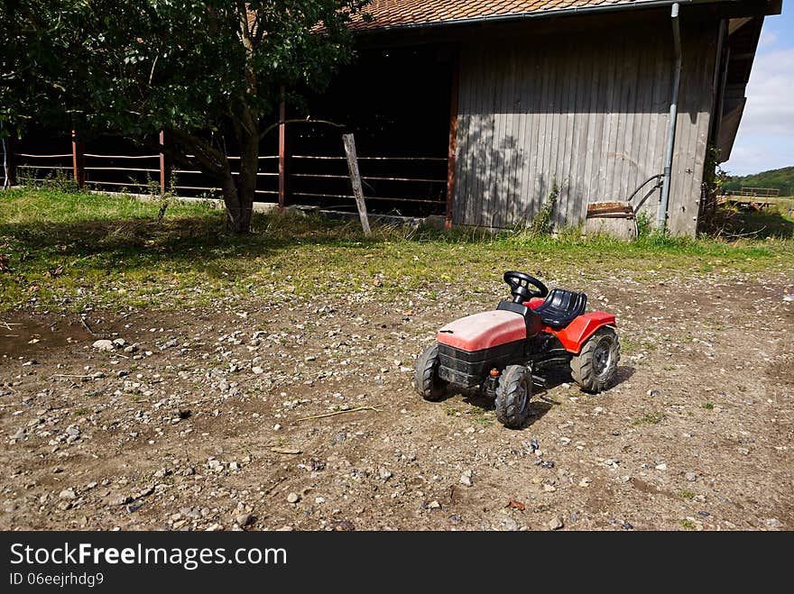 Kids children's plastic toy tractor in a big agriculture farm. Kids children's plastic toy tractor in a big agriculture farm