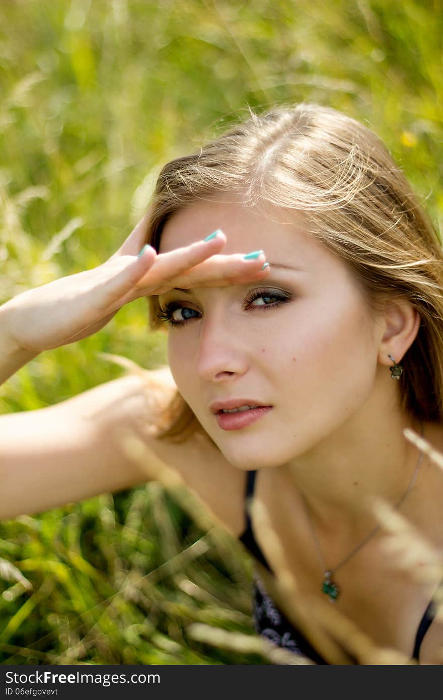 Pretty woman&#x27;s face in sunshine summer field