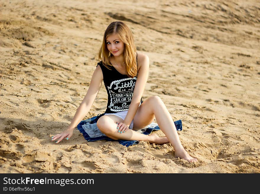 Lonely smiling girl relaxing on the sunny sea sand beach