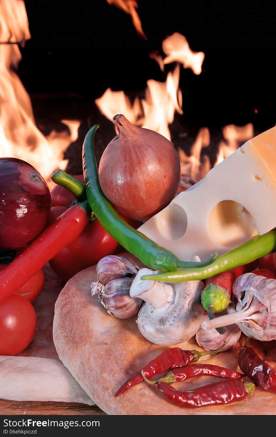 Fresh Bread and Vegetables on a Wooden Panel front of an Open fire. Fresh Bread and Vegetables on a Wooden Panel front of an Open fire