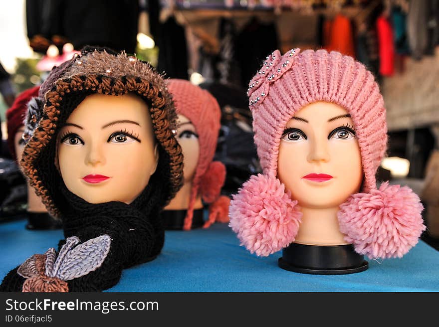 Multiple mannequin heads on a table with knitted hats. Multiple mannequin heads on a table with knitted hats