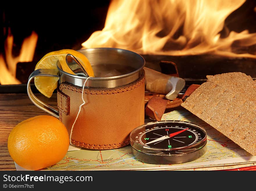 Compass, Map, Mug of Tea, crisp bread and mandarin on a Wooden Plank at Campfire. Compass, Map, Mug of Tea, crisp bread and mandarin on a Wooden Plank at Campfire