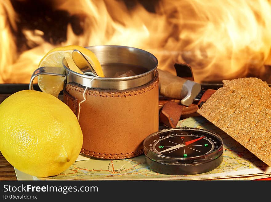 Compass, Map, Mug of Tea, crispbread, knife and lemon on a Wooden Plank at Campfire. Compass, Map, Mug of Tea, crispbread, knife and lemon on a Wooden Plank at Campfire