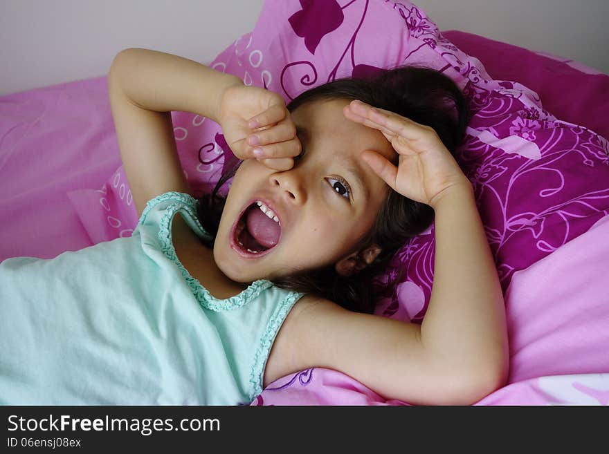 A young Asian girl yawns, rubs her eye and stretches her left arm as she awakens from a sleep. A young Asian girl yawns, rubs her eye and stretches her left arm as she awakens from a sleep.