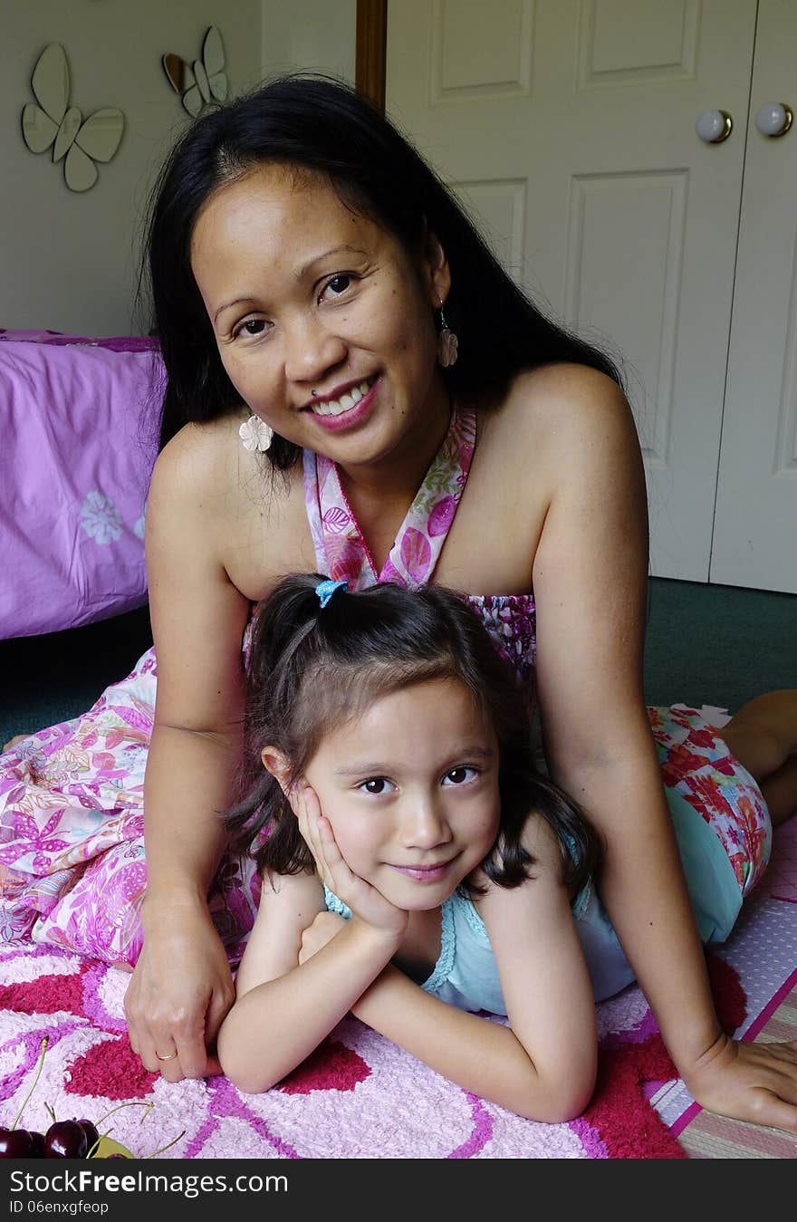 A Filipino mother and her daughter spend time together relaxing in the girls bedroom. A Filipino mother and her daughter spend time together relaxing in the girls bedroom.