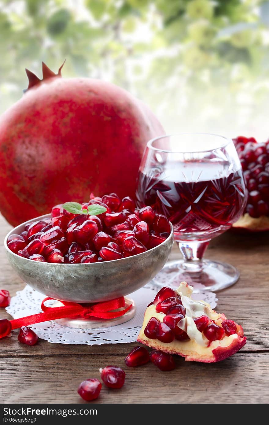 Pomegranate slice, grain and juice on the table at the summer background