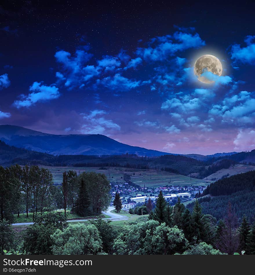 Autumn landscape at night. village on the hillside. forest on the mountain covered with red and yellow leaves. over the mountains the beam of light falls on a clearing at the top of the hill. Autumn landscape at night. village on the hillside. forest on the mountain covered with red and yellow leaves. over the mountains the beam of light falls on a clearing at the top of the hill.