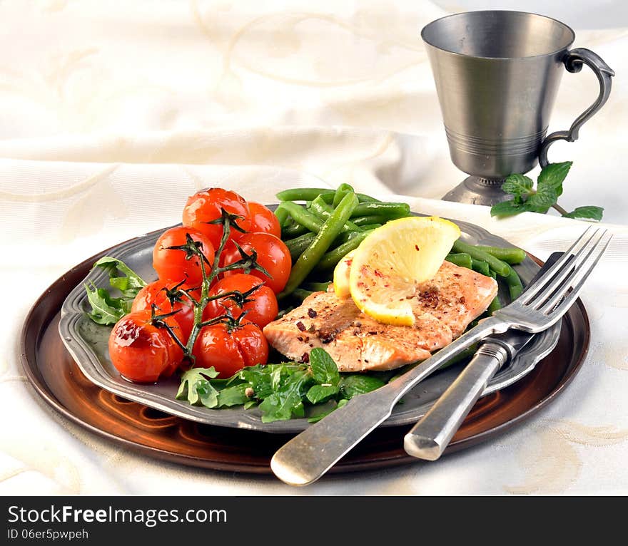 Salmon with green beans and tomatoes on a silver plate