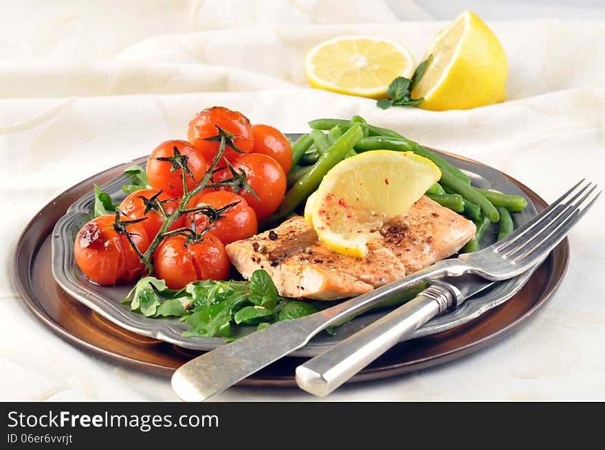 Salmon with green beans and tomatoes on a silver plate