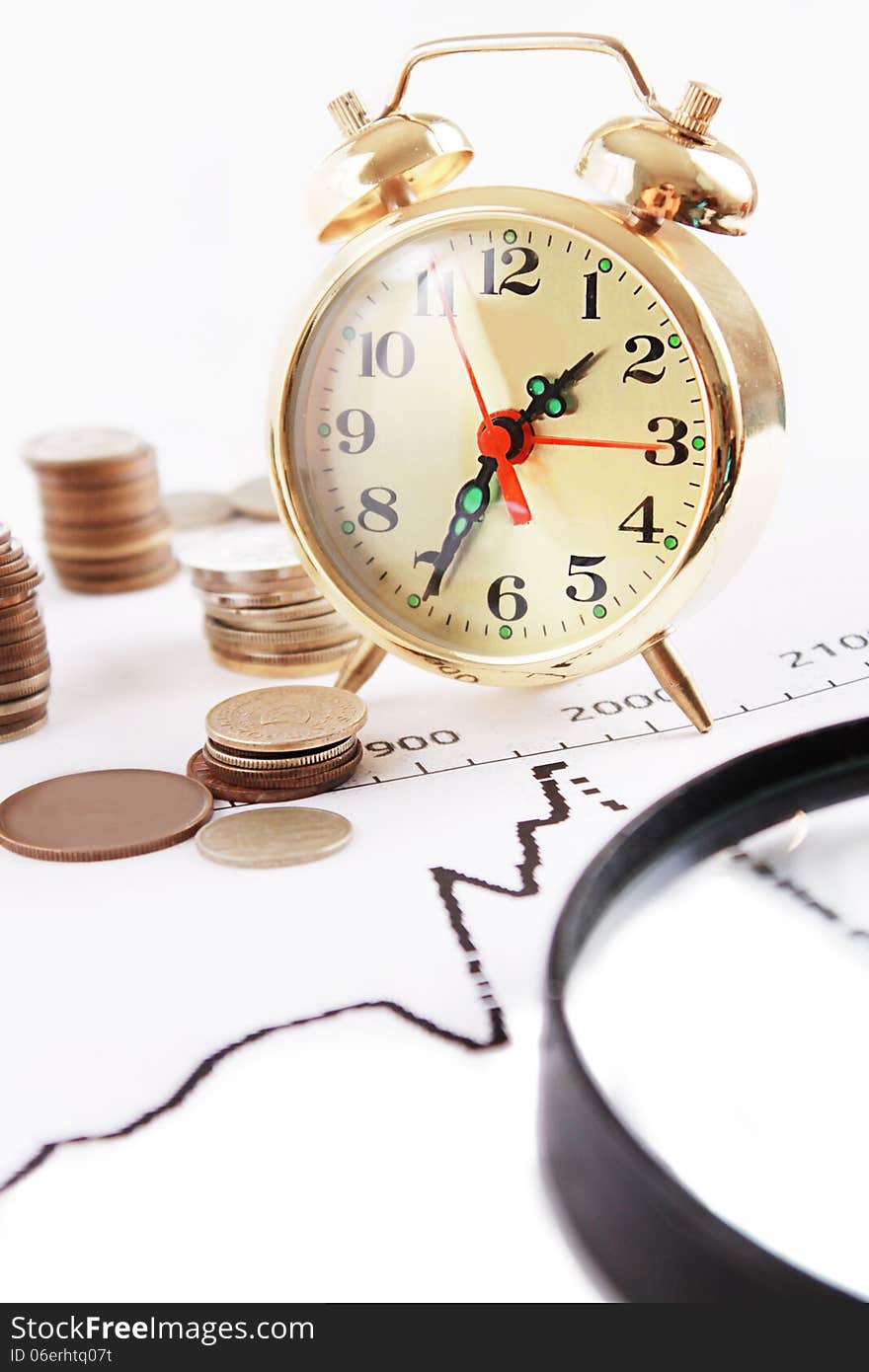 Magnifying glass, alarm clock with pile of coins on growth graphics