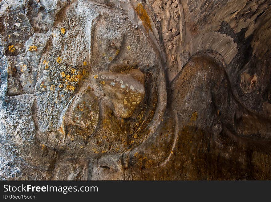 The stucco of ancient reclining Buddha at the Khao Ngu Cave in T