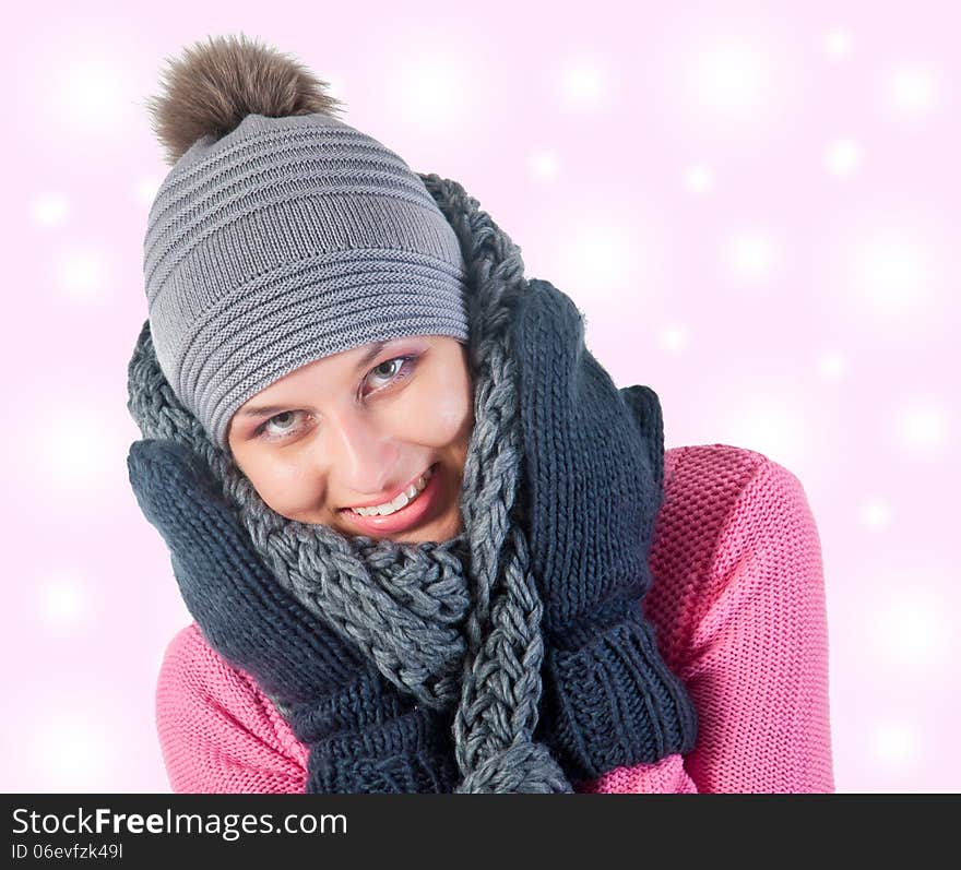 Beautiful woman in warm clothing closeup portrait. pink and snowly background