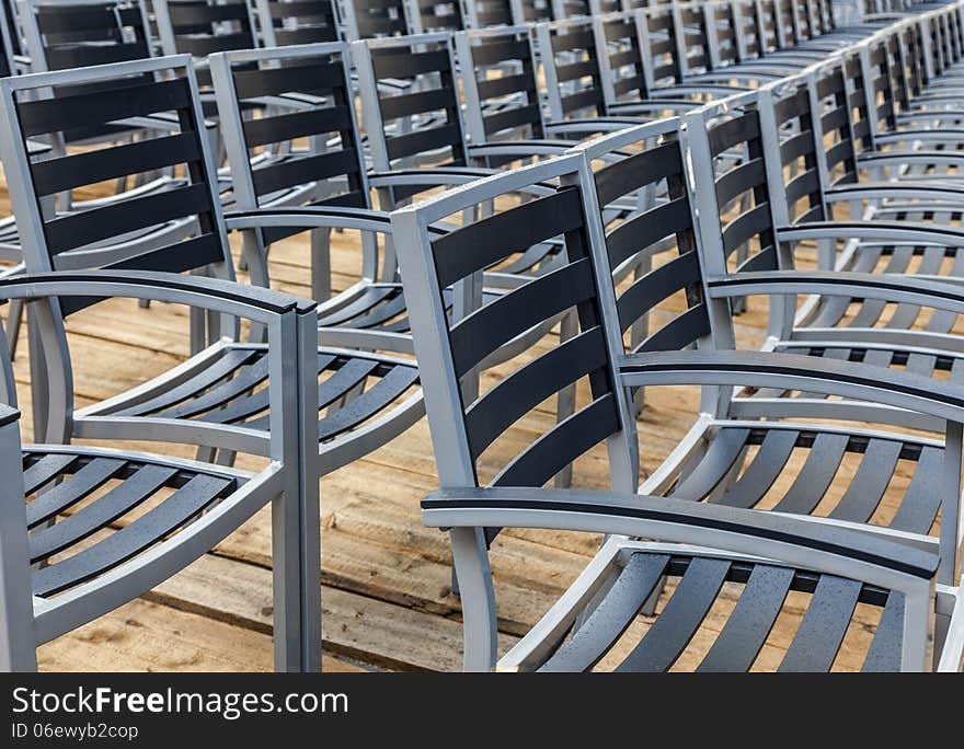 Row of wet chairs on a wooden floor located outdoors in a rainy day. Row of wet chairs on a wooden floor located outdoors in a rainy day.