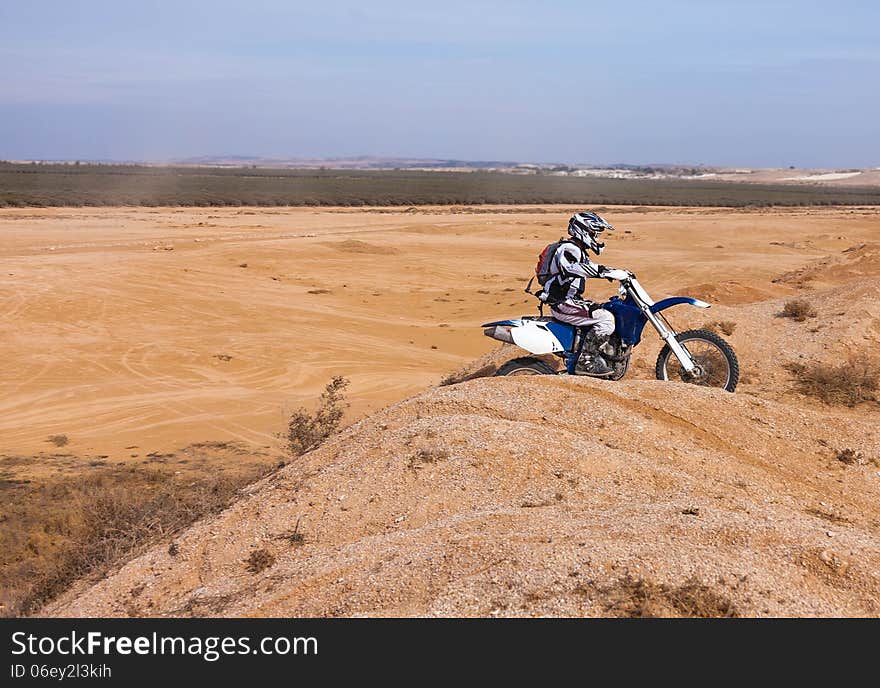 Rider on his bike rides through the hills of the desert