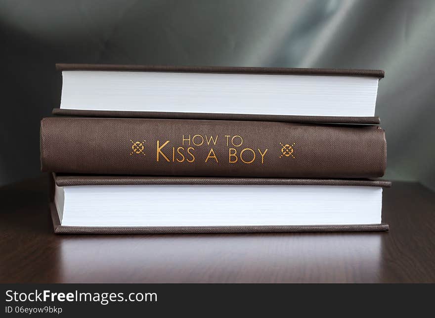 Books on a table and one with How to kiss a boy cover. Book concept. Books on a table and one with How to kiss a boy cover. Book concept.