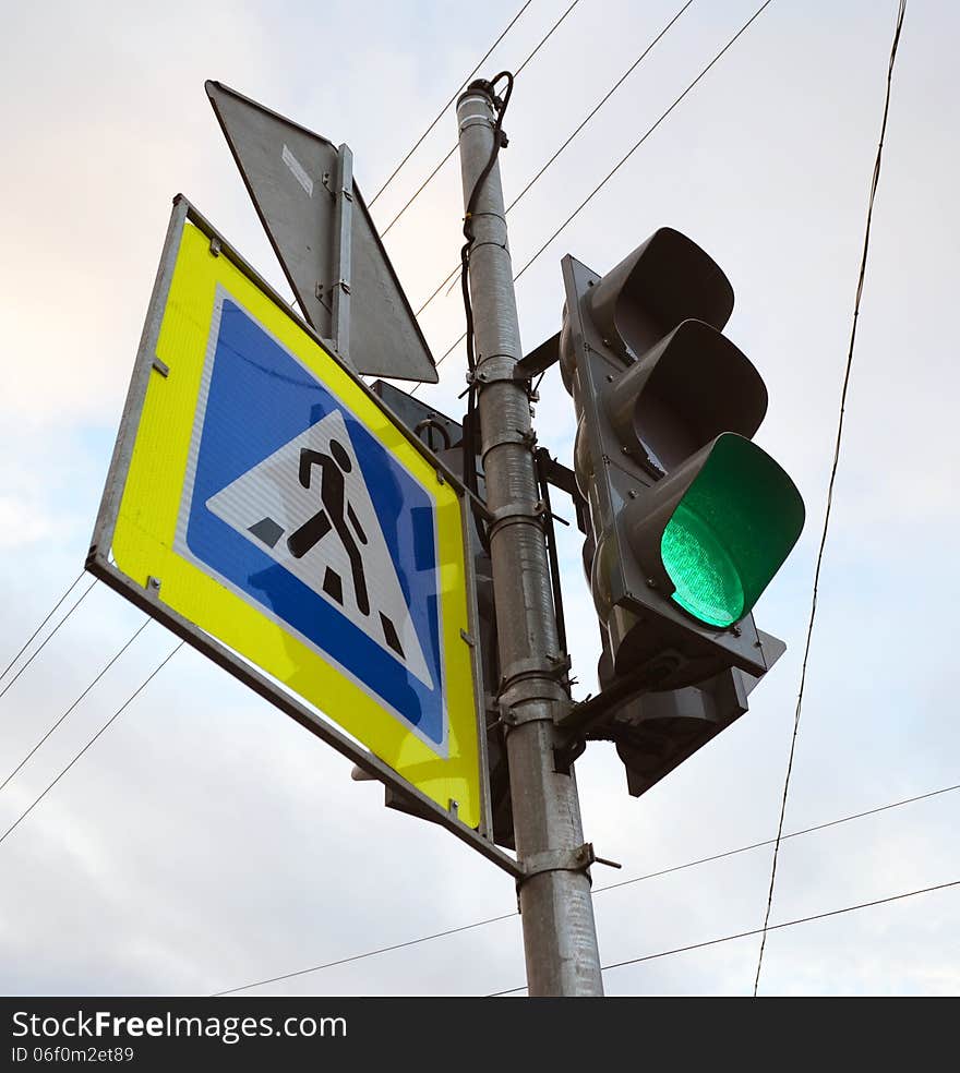 Road signs at the crosswalk. the traffic light and the sign which is visually representing the crosswalk.