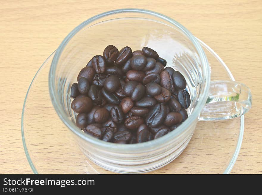 Coffee beans in cup on wood table background