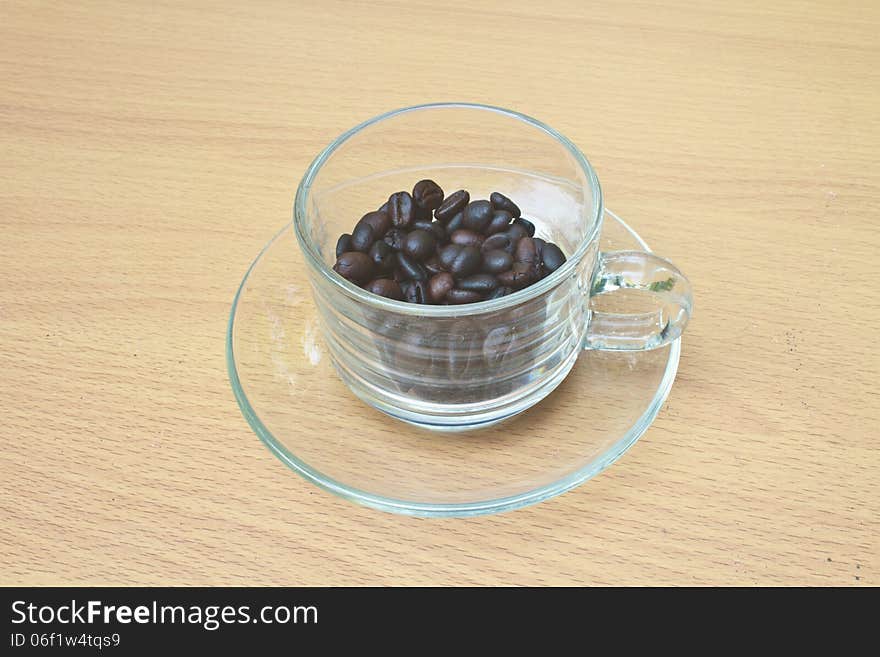 Coffee beans in cup on wood table background