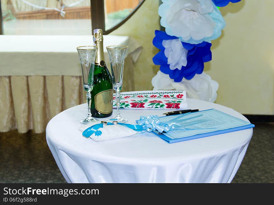 Wedding table with rings, blue stripe, glasses and champagne bottle