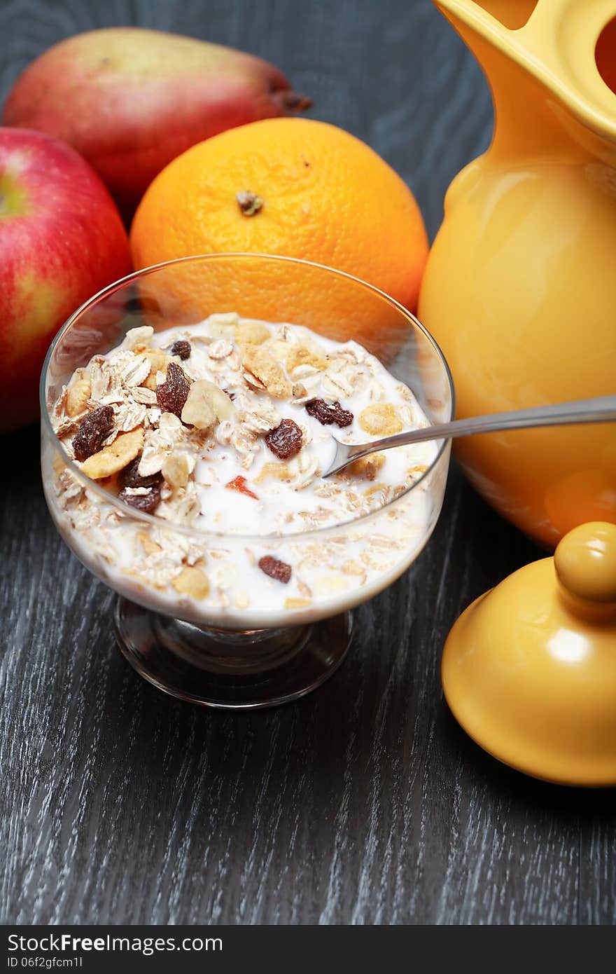 Glass bowl with muesli and milk near fruits