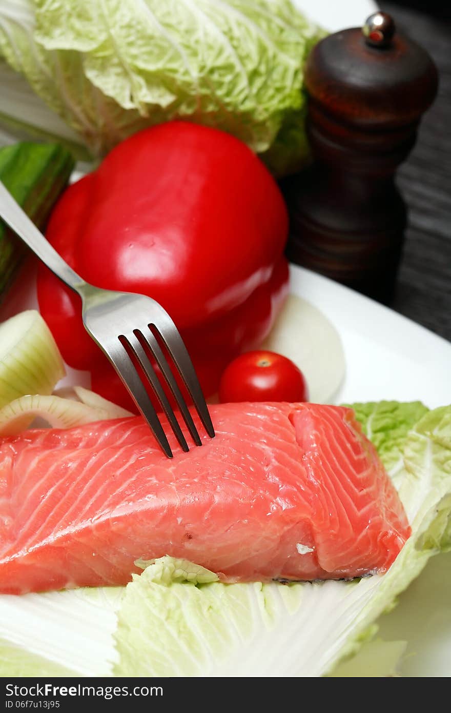 Closeup of filleted salmon and vegetables on plate near fork. Closeup of filleted salmon and vegetables on plate near fork