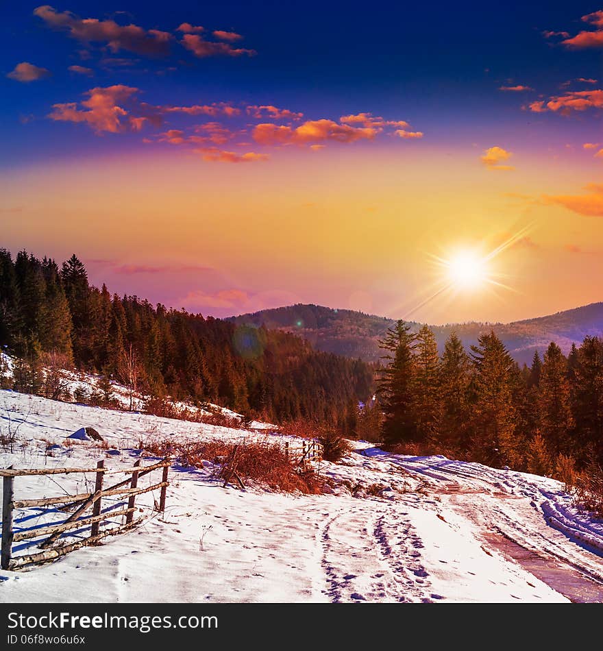 Fence by the road to forest in the mountains on a fine winter sunset. Fence by the road to forest in the mountains on a fine winter sunset