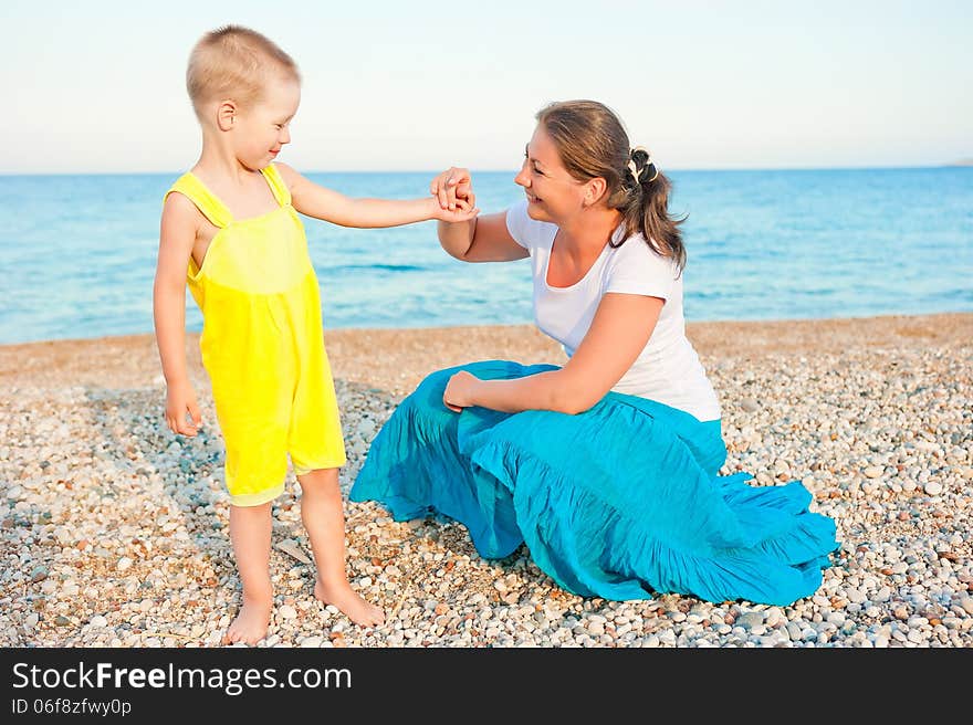 Mother with her son on a pebble beach in the evening