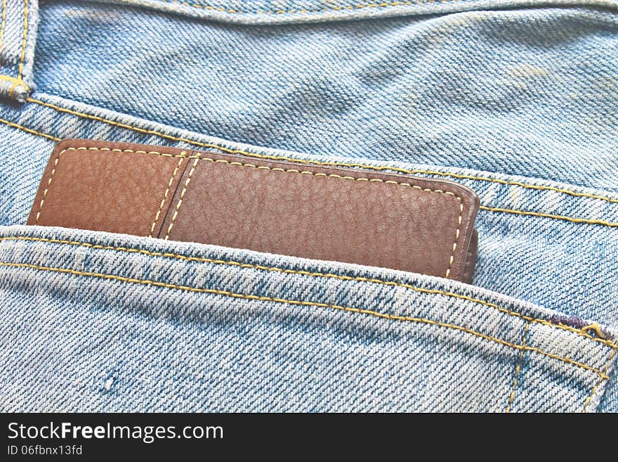 Brown wallet in jeans trousers back pocket, close up texture