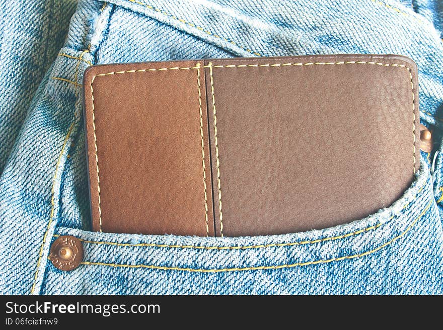 Brown wallet in jeans trousers back pocket, close up texture